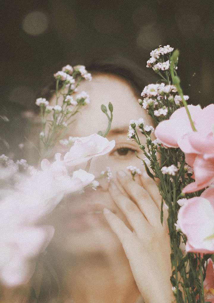 Person blickt durch Blumen